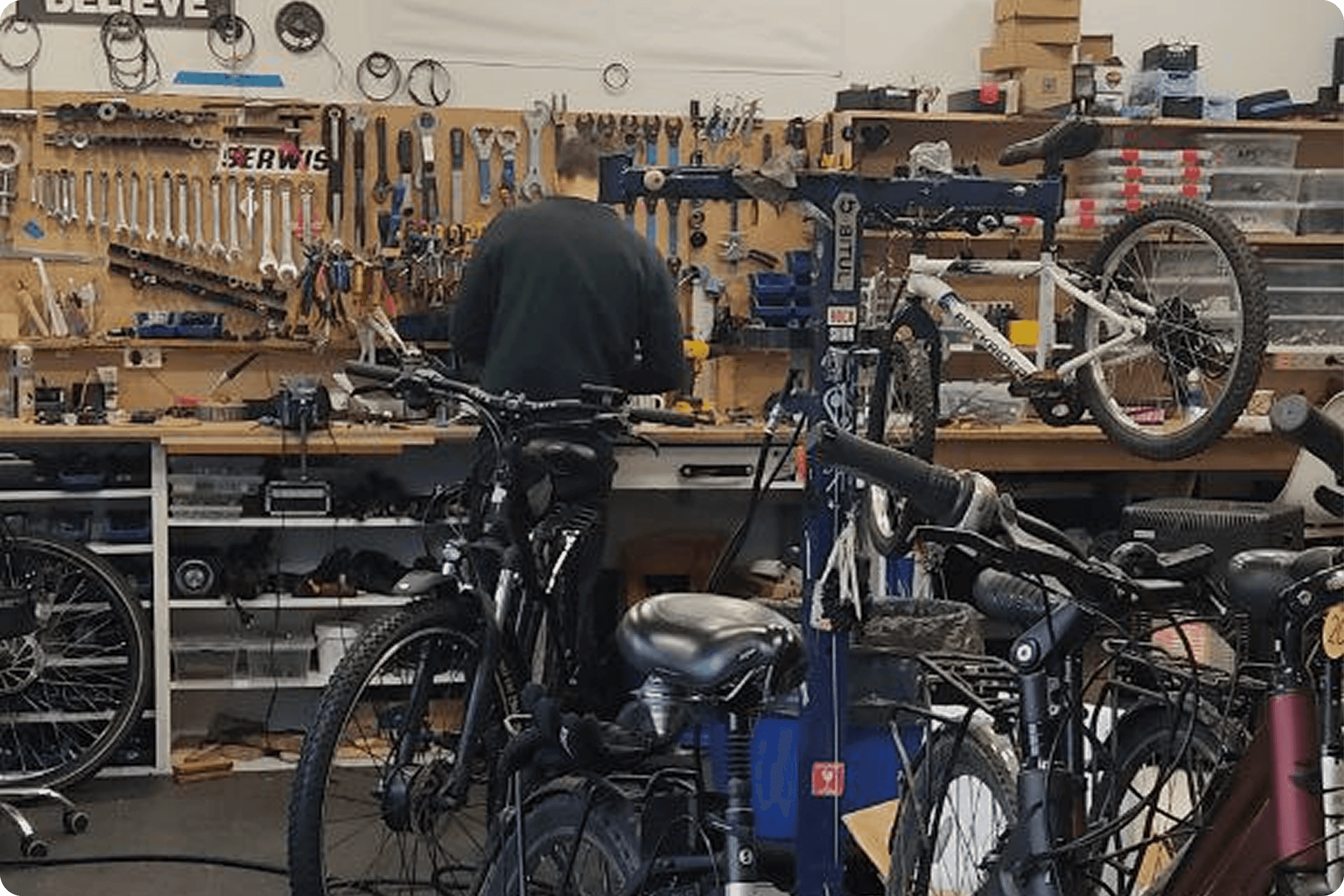 Zdjęcie wnętrza Serwisu Rowerowego NaRo w Gdańsku przedstawiające mechanika na tle ściany z narzędziami.